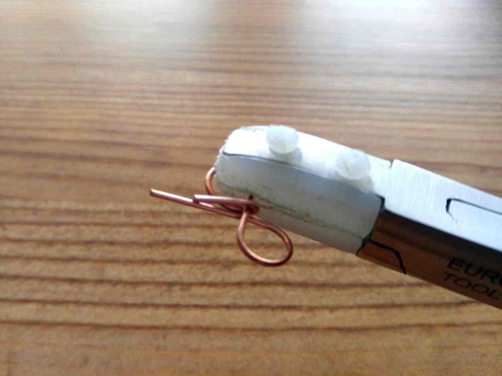 Step 4 - Wrap the ends of the wire over the center point. Trim and tighten the ends of the wire around the center point of the Infinity Loop.