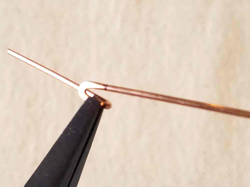 Use flat nose pliers to begin forming the V into a hook.