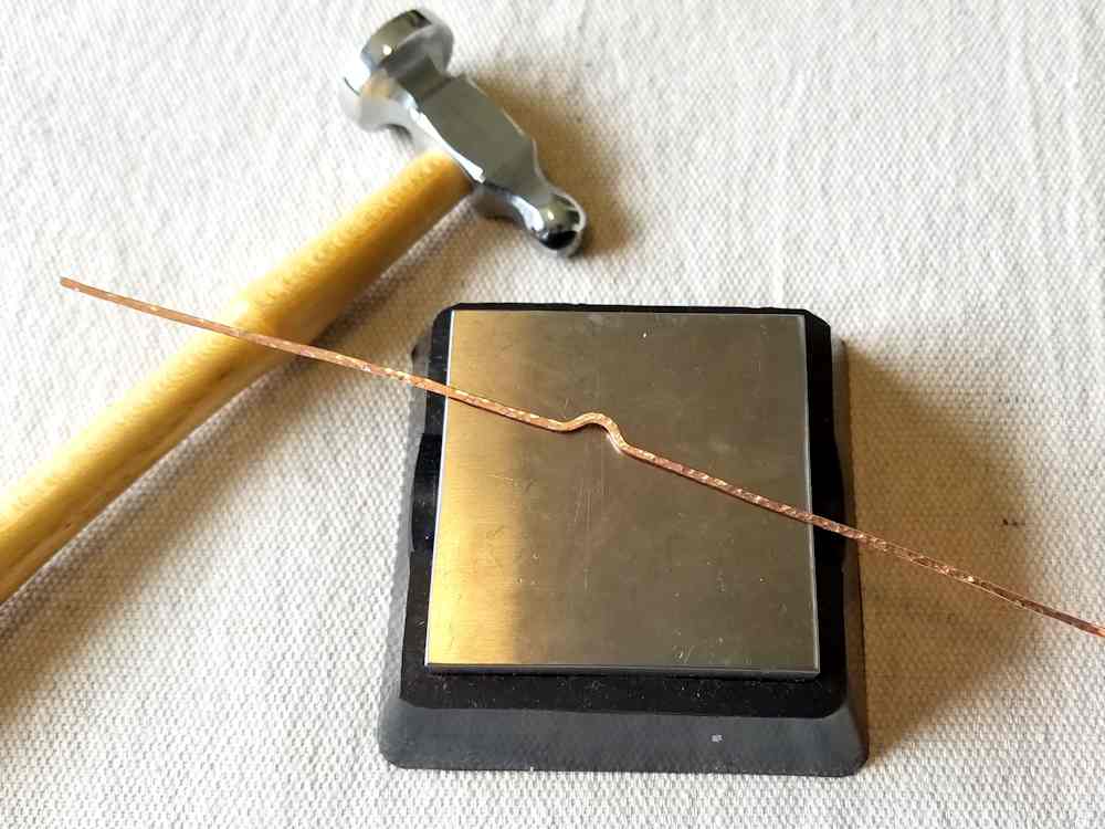 Step 16 - Use the ball end of your chasing hammer to texture the entire length of the flattened frame wire.