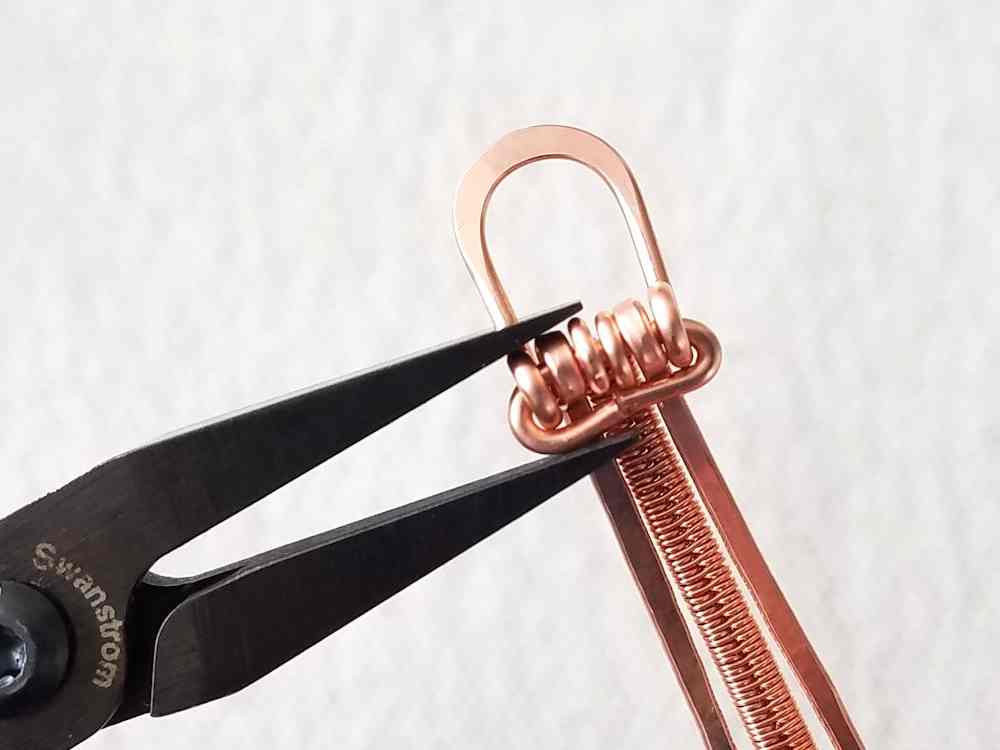 Bend the remaining end of the hinge pin around to secure the loop to the band. Trim the wire at the center of the band and use your flat nose pliers to tighten the bend and align the two ends of the hinge pin.