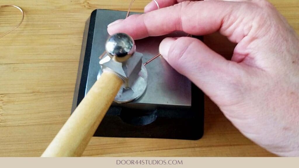 Shaping the simple heart hoop earrings with a chasing hammer and bench block