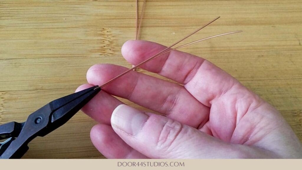 Griping the wire at the fold with flat nose pliers
